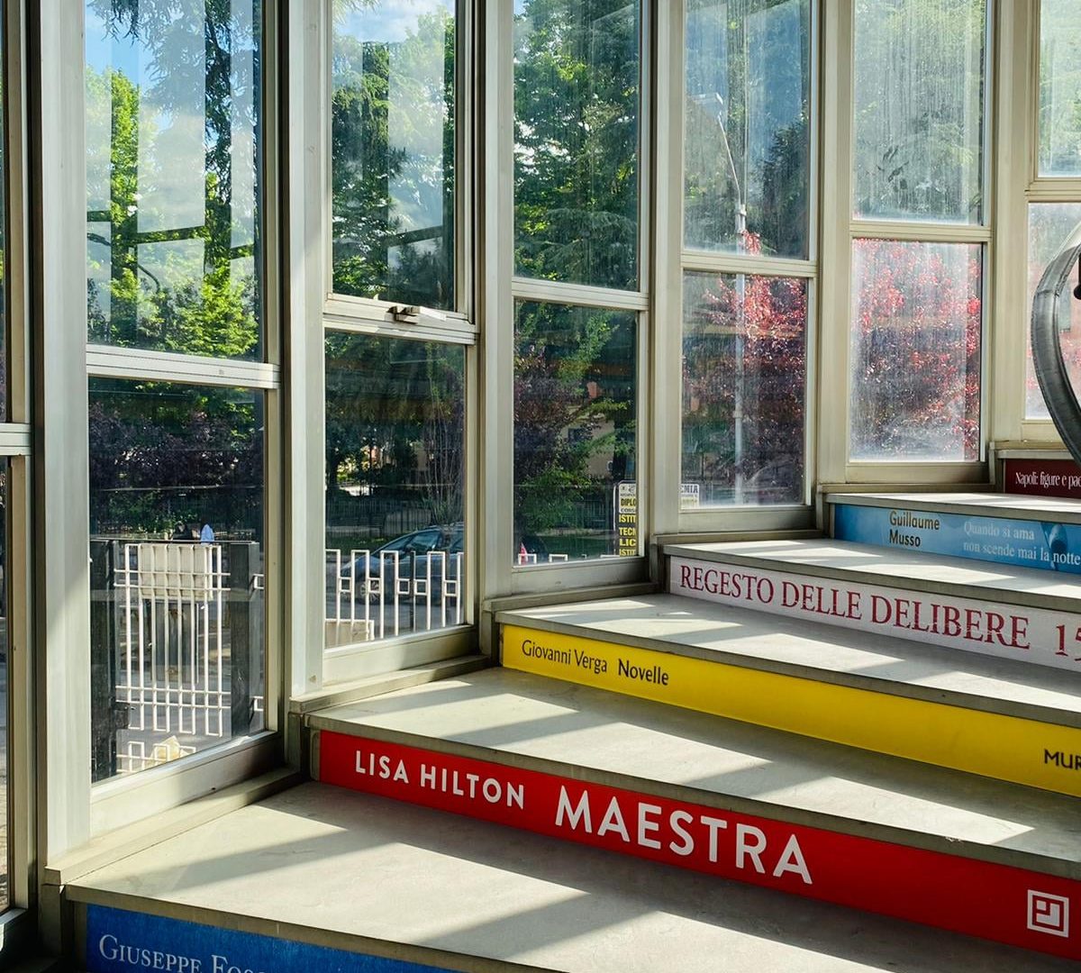 scala all'interno della biblioteca. Sui gradini sono stampati vari generi letterari